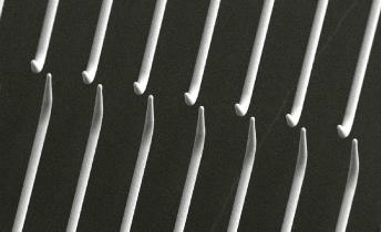 A close up SEM image of an array of 3D printed fine-pitch probes for semiconductor probe testing, produced by Exaddon